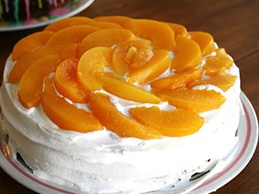смазываем поверхность торта оставшимся кремом и уркашаем дольками персиков